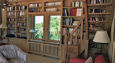 Bibliothèque avec escalier plus mezzanine en chêne dans salon de lecture / bureau.